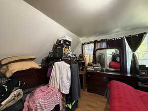Bedroom with wood finished floors and lofted ceiling