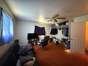 Carpeted bedroom featuring ceiling fan and a closet