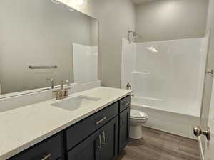 Bathroom featuring wood finished floors, vanity, toilet, and tub / shower combination