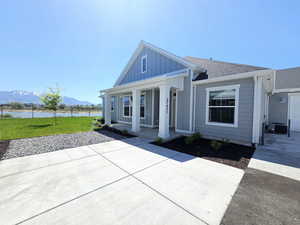 View of front of house featuring a water and mountain view, board and batten siding, covered porch, central AC, and a shingled roof