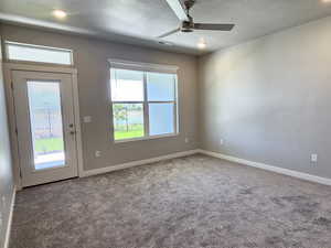 Carpeted spare room with ceiling fan, baseboards, and a textured ceiling