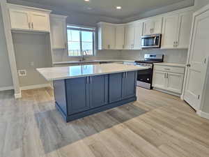 Kitchen featuring stainless steel appliances, a sink, a center island, white cabinetry, and recessed lighting