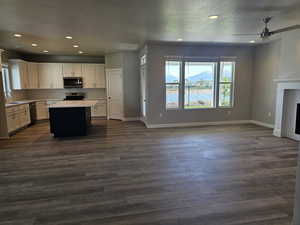 Kitchen with appliances with stainless steel finishes, open floor plan, a ceiling fan, a sink, and a textured ceiling