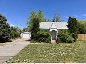 View of front of house with a detached garage, an outdoor structure, and roof with shingles