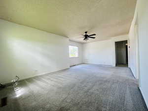 Carpeted empty room with ceiling fan, baseboards, and a textured ceiling