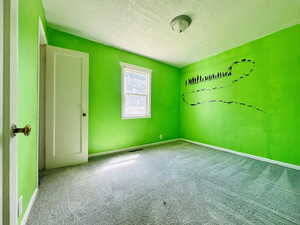 Unfurnished room featuring a textured ceiling, carpet floors, and baseboards