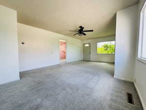 Unfurnished room with light carpet, a ceiling fan, a textured ceiling, and baseboards