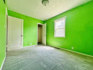 Unfurnished bedroom with carpet, a textured ceiling, and baseboards