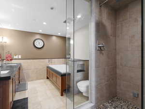 Primary bathroom featuring tile walls, a tile shower, double vanity, recessed lighting, and tile flooring