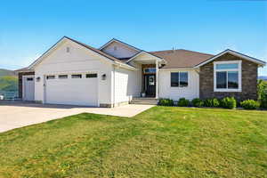 Single story home featuring an attached garage, driveway, a front lawn, and stone siding