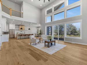 Living room featuring a high ceiling, light wood-style floors, baseboards, a ceiling fan, and recessed lighting
