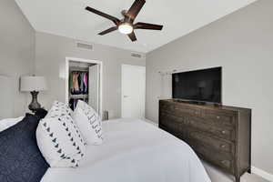 Bedroom featuring ceiling fan, a walk in closet, baseboards, and a closet