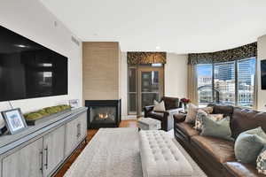 Living area with dark wood-style floors and a warm lit fireplace