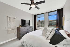Bedroom featuring light colored carpet, baseboards, and ceiling fan