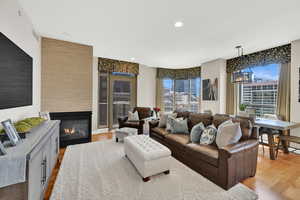 Living area featuring light wood-style floors, a glass covered fireplace, and recessed lighting