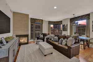Living area featuring light wood finished floors, a glass covered fireplace, and recessed lighting
