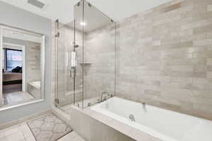 Bathroom featuring tile patterned floors, a garden tub, ensuite bath, a shower stall, and baseboards