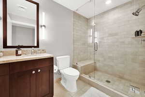 Full bath with a shower stall, tile patterned floors, toilet, vanity, and baseboards