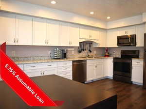 Kitchen with appliances with stainless steel finishes, a sink, white cabinetry, dark wood-style flooring, and recessed lighting
