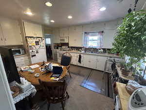 Kitchen featuring white appliances, recessed lighting, white cabinets, a sink, and light countertops