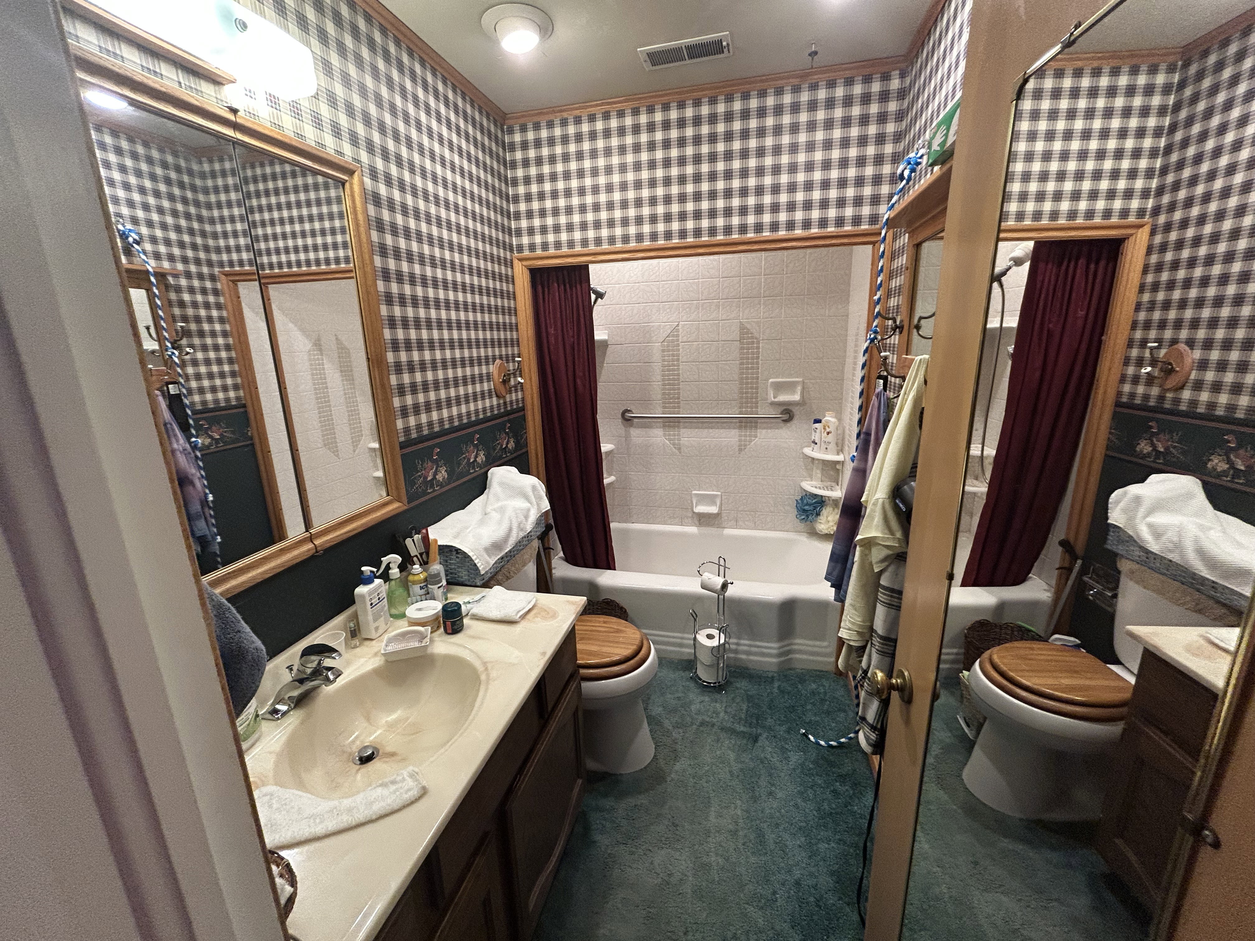 Full bathroom with toilet, vanity, shower / bath combo, and wallpapered walls
