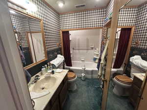 Full bathroom with toilet, vanity, shower / bath combo, and wallpapered walls
