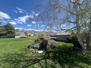 View of green lawn featuring a mountain view and an outdoor structure