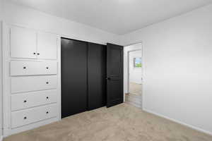 Unfurnished bedroom with light colored carpet and baseboards