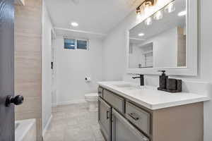 Bathroom featuring vanity, toilet, baseboards, tile patterned flooring, and recessed lighting