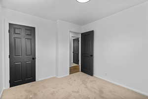 Unfurnished bedroom with carpet flooring and baseboards