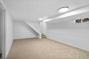 Bonus room with carpet floors, stairway, and a wainscoted wall