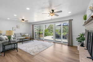 Living room featuring a ceiling fan, plenty of natural light, recessed lighting, wood finished floors, and crown molding