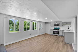 Kitchen with stainless steel appliances, gray cabinets, a sink, light countertops, and healthy amount of natural light
