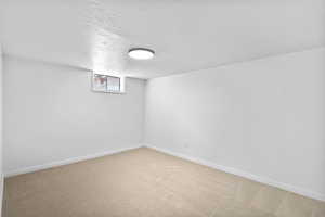 Basement with carpet, baseboards, and a textured ceiling