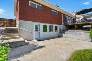 Rear view of house with brick siding, a patio, and a wooden deck