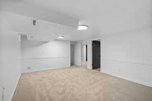Finished below grade area featuring carpet, wainscoting, and a textured ceiling