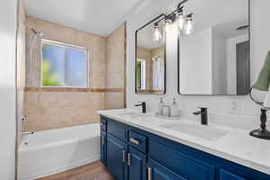Full bath with shower / washtub combination, double vanity, and wood finished floors