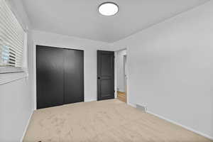 Unfurnished bedroom featuring carpet flooring, baseboards, and a closet