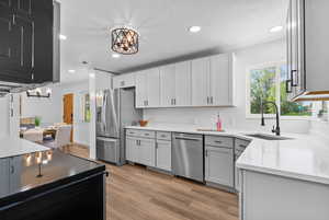 Kitchen featuring appliances with stainless steel finishes, a sink, a chandelier, recessed lighting, and light wood-type flooring