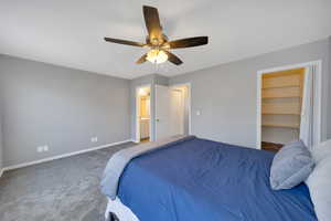 Bedroom featuring carpet flooring, a walk in closet, a ceiling fan, and connected bathroom