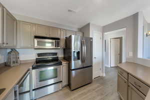 Kitchen featuring stainless steel appliances, light countertops, light wood laminate flooring