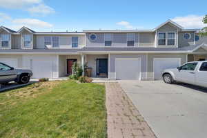 View of property with driveway, a front yard, and an attached garage