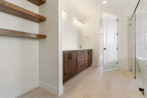 Full bathroom featuring a shower stall, double vanity, baseboards, and recessed lighting