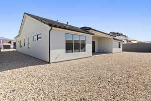 Rear view of house with fence, stucco siding, and a patio