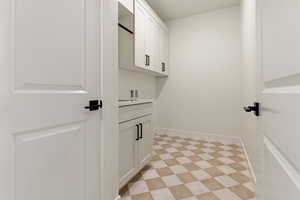 Washroom featuring cabinet space, hookup for a washing machine, and baseboards