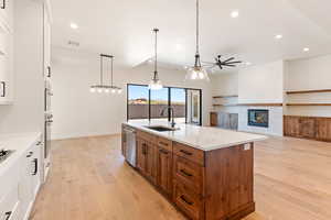 Kitchen with a sink, ceiling fan, recessed lighting, brown cabinets, and light wood-style floors