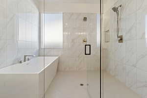 Full bathroom featuring a shower stall, a freestanding tub, and tile walls