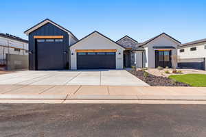 View of front of home with an attached garage, concrete driveway, board and batten siding, and stucco siding