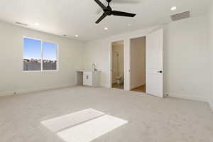 Unfurnished bedroom featuring light carpet, recessed lighting, baseboards, ensuite bath, and a sink