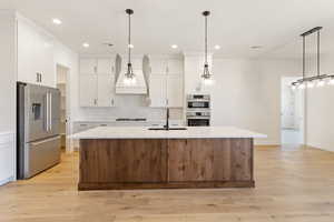 Kitchen with stainless steel appliances, a sink, recessed lighting, backsplash, and white cabinets